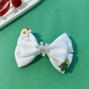 Détail de la pince à cheveux nœud de Noël avec motifs Père Noël et flocons de neige