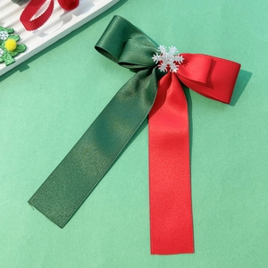 Detail of Christmas bow hair clip with red and green satin ribbons and silver snowflake