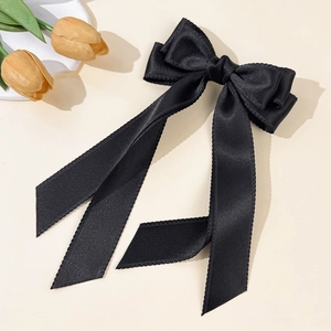 Detail of elegant black satin bow hair clip with long ribbons and scalloped edges