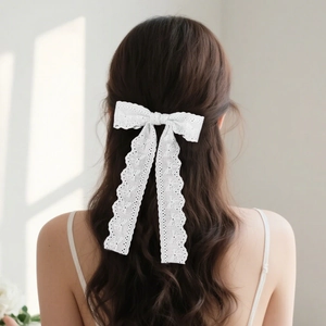 Elegant white lace bow hair clip with long wavy streamers on wavy brunette hair