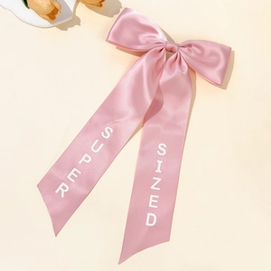 Elegant pink satin bow hair clip with long ribbons featuring Super Sized white letters