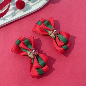 Paire de nœuds de Noël rouges et verts avec grelots dorés sur fond de fête rouge texturé