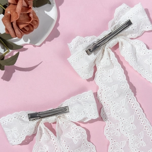 Elegant white lace bow hair clips set with romantic embroidery on a soft pink background
