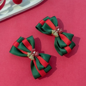 Détail des barrettes de Noël à nœuds superposés rouge et vert avec petites cloches dorées