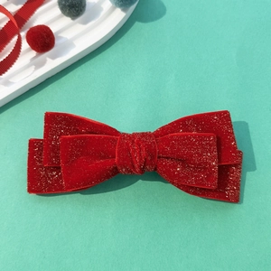 Detail of red velvet bow hair clip with gold glitter texture and double-layered structure
