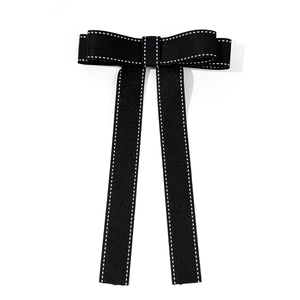 Detail of a black bow tie with white stitching and long ribbons for shirts and hair