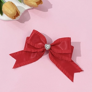 Gros plan d'une pince à cheveux en satin rouge avec strass coeur et bords à volants soignés
