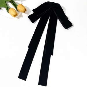 Dettaglio del grande fiocco in velluto nero con lunghi nastri eleganti su sfondo bianco