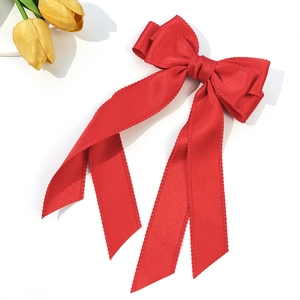 Detail of red satin bow hair clip featuring elegant scalloped lace edges for women