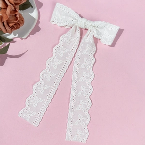 Detailed close-up of white lace bow hair clip with butterfly embroidery and long tassels