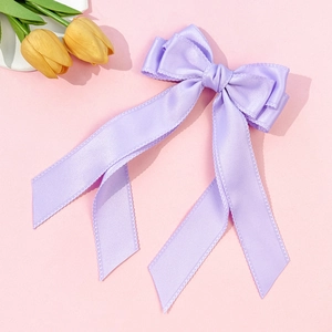 Detail of lavender satin bow hair clip with long ribbons on pink background