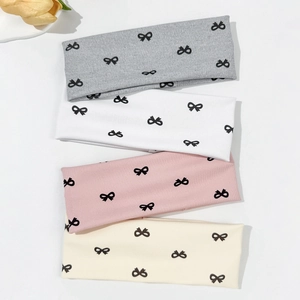 Detailed set of four elastic headbands with black bow patterns in soft ribbed knit