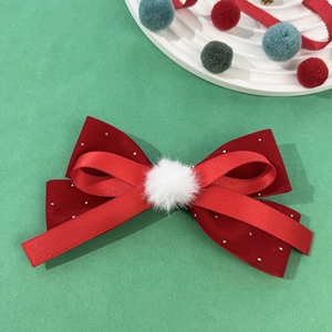 Detail view of red velvet bow hair clip with silver beads and white pom-pom for Christmas