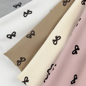 Close-up of ribbed fabric headbands with bow print in grey, white, khaki, and pink
