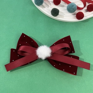 Detail of red velvet bow hair clip with silver beads and a plush white pom-pom