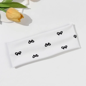 Close-up of white elastic headband featuring black bow prints and ribbed knit texture