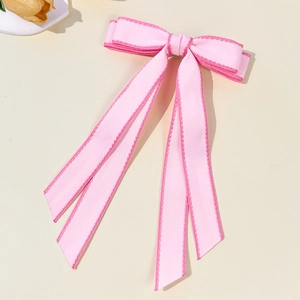 Détail d'une pince à cheveux à double nœud rose avec surpiqûres et de longs rubans