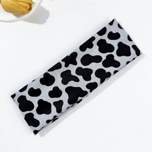 Detalle de diadema elástica con estampado de vaca y textura de punto suave para deporte