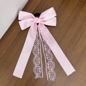 Detailed close-up of pink silk ribbon bow hair tie with delicate lace lace edges