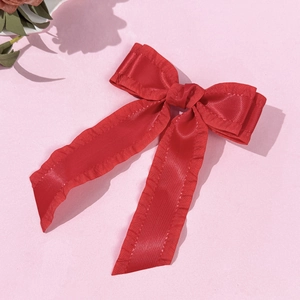 Barrette à cheveux élégante en satin rouge avec bords volantés sur fond texturé rose