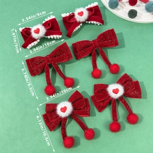 Trois barrettes à nœuds rouges en velours et paillettes avec pompons sur fond vert