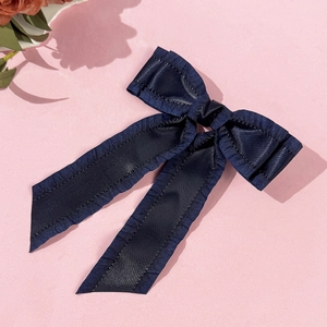 Détail d'un nœud papillon bleu marine en satin avec bords plissés sur fond rose cerisier