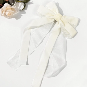 Detailed macro of cream velvet and organza layers on an elegant bow hair clip