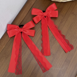 Detail of red satin bow hair ties with delicate lace edges on a wooden texture