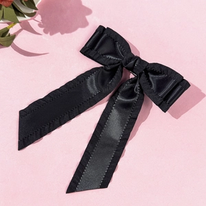 Détail de la pince à cheveux noeud en satin noir avec bords brodés et longs rubans