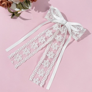 Barrette nœud en dentelle blanche avec broderies florales et rubans sur fond rose