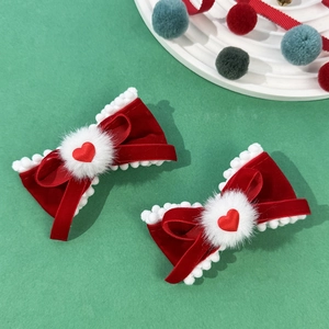 Détail de pinces à cheveux en velours rouge avec pompons blancs et cœur pour coiffure de fête
