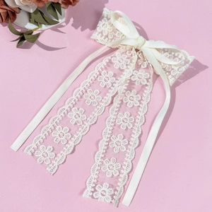 Vue détaillée d'un nœud en dentelle beige clair avec broderie florale et rubans en satin