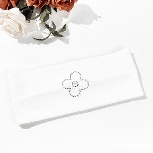 Macro shot of white elastic headband featuring a sparkling rhinestone clover pattern design