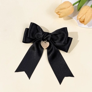 Nahaufnahme einer eleganten schwarzen Haarschleife aus Satin mit herzförmigem Goldanhänger