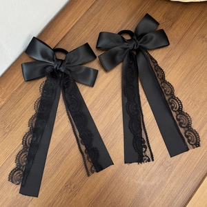 Detail of black satin bow hair ties with delicate lace ribbons on a wooden background
