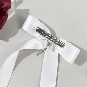 White satin bow hair clip with a silver metal cross pendant and alligator grip