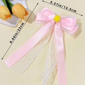 Detail showing pink ribbon hair clip with white lace trim and yellow star decoration