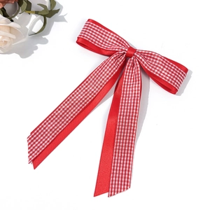 Détail d'un nœud papillon à carreaux rouge et blanc avec de longs rubans sur fond blanc