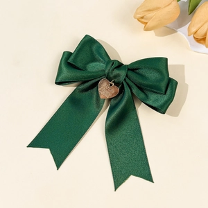 Nahaufnahme der dunkelgrünen Satin-Schleife Haarklammer mit goldenem Herzanhänger Detail