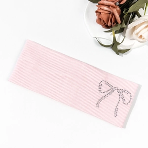 Detail of pink ribbed knit headband featuring a sparkling rhinestone bow pattern decoration