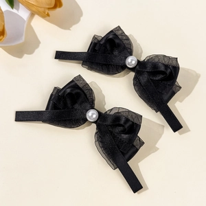 Détail de deux barrettes à nœud noir avec ruban en maille et accents de perles blanches