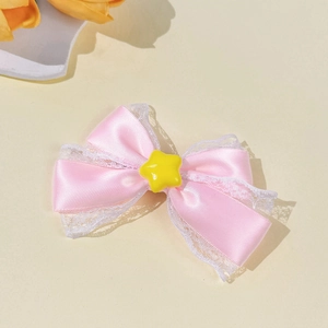 Close-up of pink ribbon hair clip with delicate white lace edges and a yellow star center