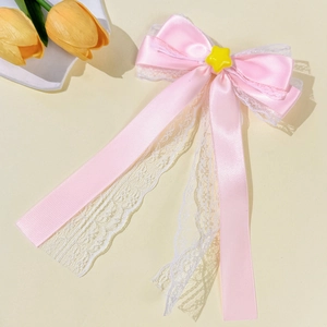 Detail of pink satin bow hair clip with white lace trim and a yellow star charm