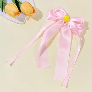 Sweet pink satin bow hair clip with yellow star accent and floral decorative background