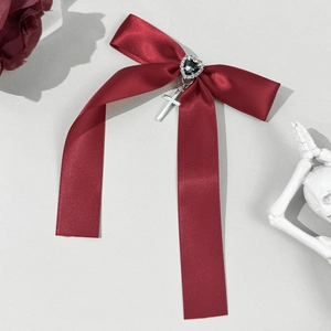 Detail of burgundy satin bow hair clip with heart crystal and silver cross pendant
