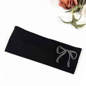 Close-up of black ribbed knit headband featuring a sparkling rhinestone bow decoration