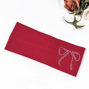 Detail of red knitted headband featuring a silver rhinestone bow and ribbed texture