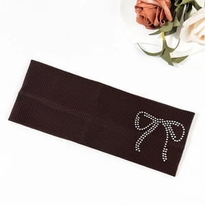 Detail of dark brown ribbed knit headband featuring a sparkling rhinestone bow accent
