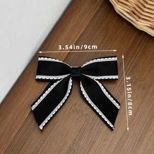 Dettaglio del fiocco nero per capelli con cuciture bianche e misure di 9x8 cm