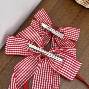Set of two red gingham bow hair clips with silver alligator grips on wood surface